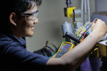 Smiling Technician Holding Digital Multimeter in Electronics Workshop