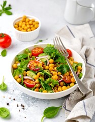 Vibrant chickpea salad bowl with mixed greens, tomatoes, cucumber, and onions