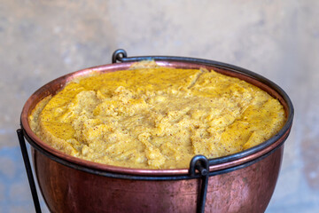 Copper Pot Holding Delicious Italian Polenta with Wooden Spoon