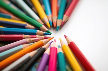 Fototapeta premium Colored pencils on a plain white surface, close-up with selective focus and blurred background