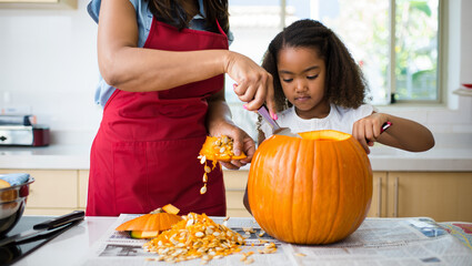 Smiling woman and girl joyfully carve pumpkin together in cozy kitchen. AI generated.
