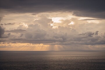 Overcast sky above the water body with sunlight piercing through clouds
