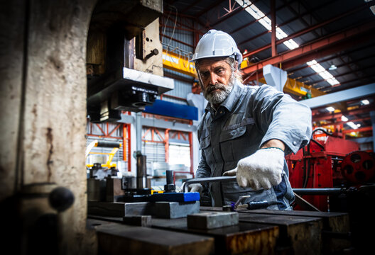 Technician industrial worker inspecting aluminum metal sheet fabricating roll check stock materials in the steel coil storage area, rolls metal sheet high quality durable meet standards industry.