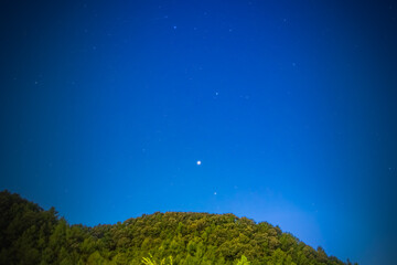 Stars begin to appear in the blue sky of early evening.