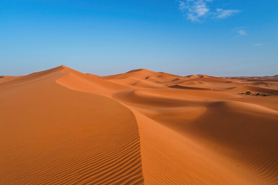 Stunning aerial shots of golden dunes under a vibrant blue sky