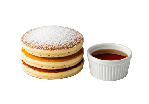 Stack of three golden-brown fluffy pancakes with powdered sugar, alongside a white ramekin of amber maple syrup, isolated on transparent, close-up, bright studio light, concept of culinary perfection