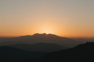 Fototapeta premium Sunrise behind a foggy mountain outline