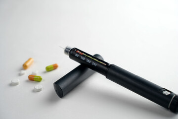 Insulin pen, capsules, and pills on a white background