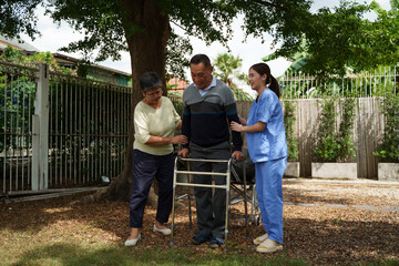 Elderly men and women happily exercise under a big tree. Elderly man holding a walker