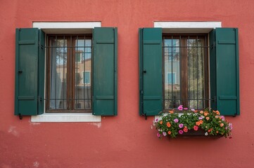 Obraz premium Vibrant painted facades with open shutters and blooming flower pots on a charming island street, ample space for text