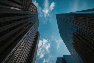 Naklejka premium Silhouetted tall buildings made of glass and concrete under an expansive sky view