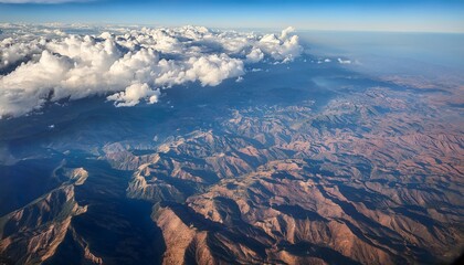 aerial view of land and clouds captured from an airplane showcasing the stunning interplay of terrain and cloud formations visible during the flight from the airplane perspective