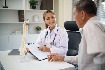 Doctor holding a clipboard explains spinal diagnosis and treatment to senior man in a clinic. Health care concept.