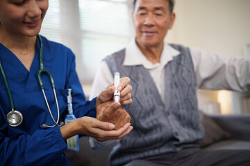 Female nurse checking a senior patient blood sugar levels during a home care visit.