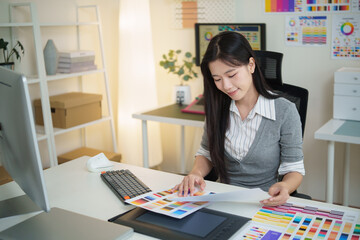 Young creative professional analyzing color palettes and charts during design project.