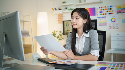 Young creative professional analyzing color palettes and charts during design project.