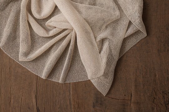 Delicate mesh lace fabric spread over a rustic wooden surface, showcasing intricate texture and elegant draping