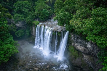 Obraz premium Aerial perspective of a tropical waterfall surrounded by lush greenery and ocean views