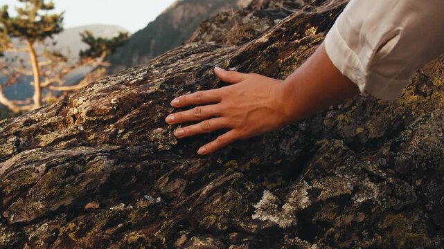 woman hand touching stone rock. hand close up. texture of ancient rocks mountains nature. traveler girl climbing rocks at sunset summer. panoramic view city capital Andorra la Vella. moss-grown stone