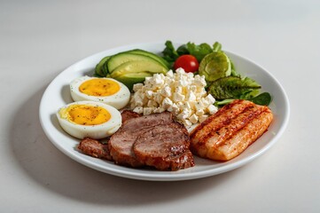 Low carbohydrate meal with baked protein, eggs, avocado, leafy greens, cheese, and seafood.