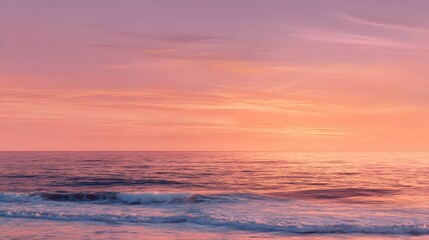 Obraz premium A tranquil seascape at sunset, showcasing soft pink and orange hues across the sky and water.