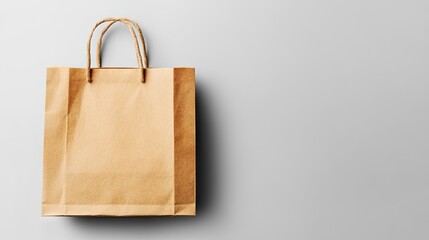 A light brown paper shopping bag with twisted paper handles sits on a plain light grey background, angled slightly to the left.  Plenty of negative space is visible to the right