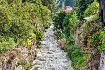 View of the Urubamba River flowing through the Sacred Valley alongside the Ollantaytambo town, Peru.