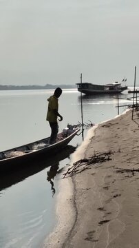 Local man fishing with net on wooden boat along Mekong River