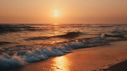 A golden sunset paints the tranquil ocean shoreline, showcasing soft waves gently kissing the sandy beach.