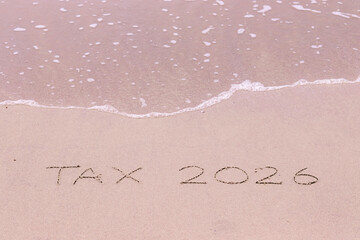 Fototapeta premium TAX 2026 handwritten with ocean waves on a sandy beach.