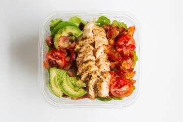 Fresh keto-friendly cobb salad in a clear container for convenient takeaway or delivery, white background, overhead shot