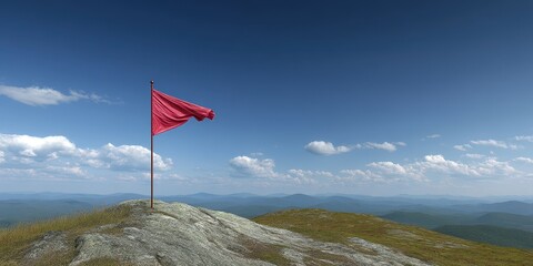Mountain Climbing Concept. Flag waving atop a mountain with a clear blue sky and distant hills.