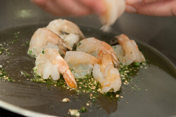 Chef de cozinha preparando um prato da culinaria mediterranea, com camaroes fritos no azeite, vinho branco e temperos
