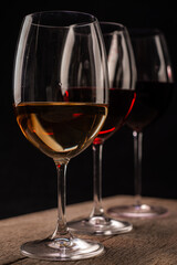 Crystal glasses with red and white wine
over rustic wooden table on black background