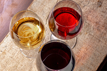 Crystal glasses with red and white wine
over rustic wooden table on black background