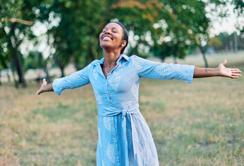 Happy young black woman meditating and daydreaming and relaxing and having fun in nature outdoors