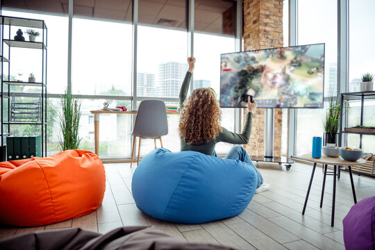 Young woman enjoying a video game session on a large screen in a modern creative indoor coworking space - Powered by Adobe