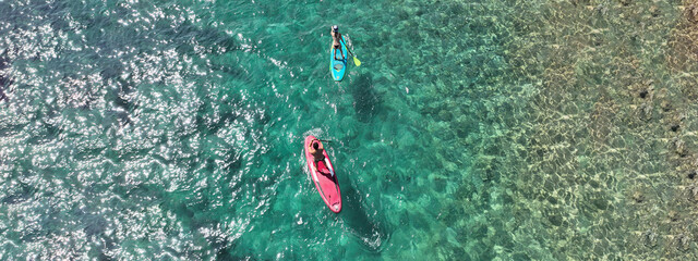 Aerial drone ultra wide photo of couple practice Stand Up Paddle board or SUP surf in tropical...