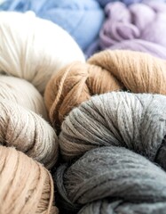 Close-up view of various balls of yarn in a range of neutral and muted tones, showcasing the textures and diversity of the fibers.