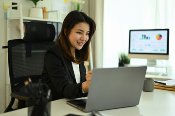 An Asian Businesswoman reviewing reports while on laptop screen, working at modern office