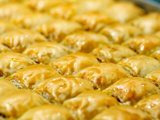 A tray of golden diamond shaped baklava is seen up close a rich and sweet traditional pastry perfect for celebrations and special occasions