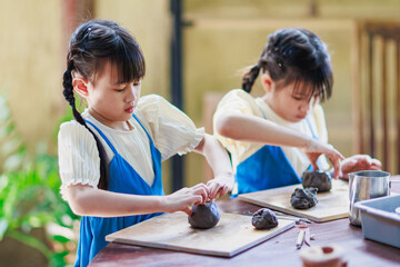Child hands sculpting clay pottery mug. Kid making clay cup handcraft workshop for hobby activity.