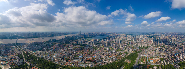 Wuhan, China city skyline panorama shows urban sprawl along river with vast landscape under cloudy sky.