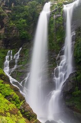 Obraz premium Stunning waterfall cascading over lush green cliffs