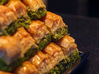 A stack of traditional Turkish baklava with a rich green pistachio filling is arranged in a tempting pyramid showcasing the popular and delicious sweet pastry