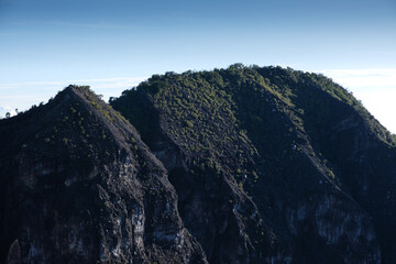 Majestic Green-Forested Volcanic Peak Under a Bright Blue Sky