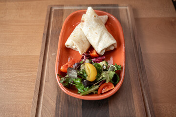Delicious wraps served with a fresh garden salad on a wooden table