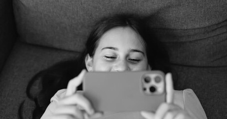 Teenager girl using smartphone for watching a reel video on social media - Technology addiction, childhood and lifestyle concept - Black and white editing