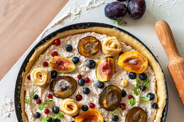 Raw tart or open summer pie with figs, prunes, apricots and blueberries is ready to bake in a round mold. Close-up. View from above. High quality photo