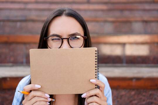 Closeup of woman female student teacher tutor hold planner copybook hiding half facial expression, copy space for advertisement. College university study programs, academic educational courses concept